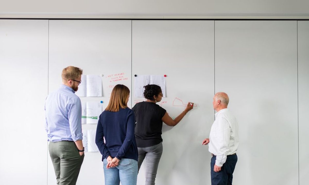 A small team planning at a whiteboard in an office