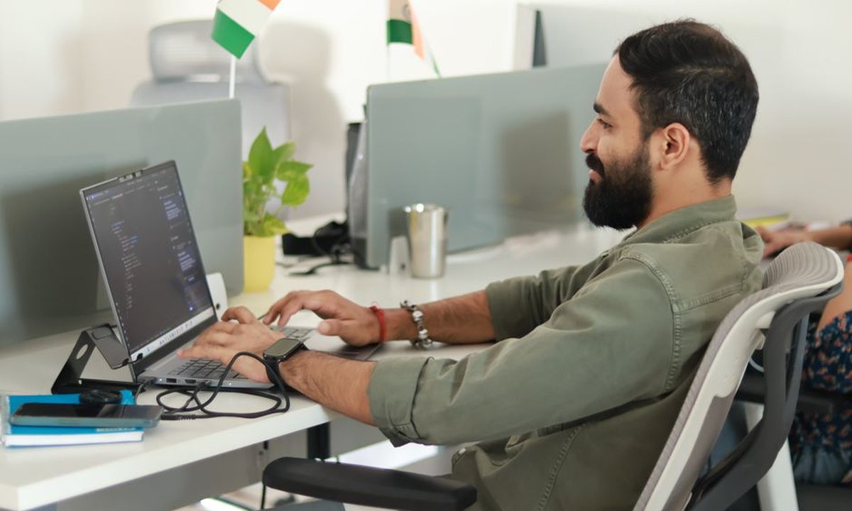 A software developer working on a laptop in a modern office