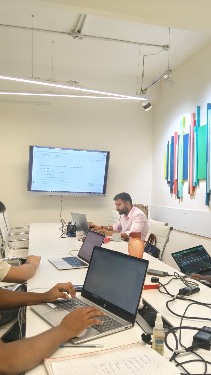 Learners follow a Python notebook on the classroom screen while writing the same code on their own laptops